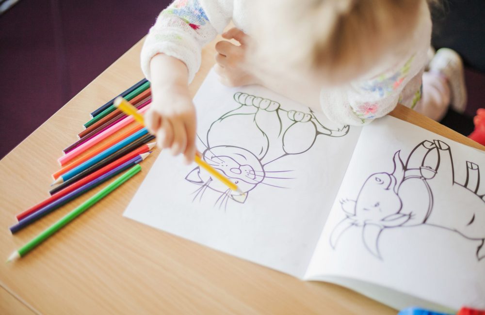 girl-holding-pencil-sitting-table